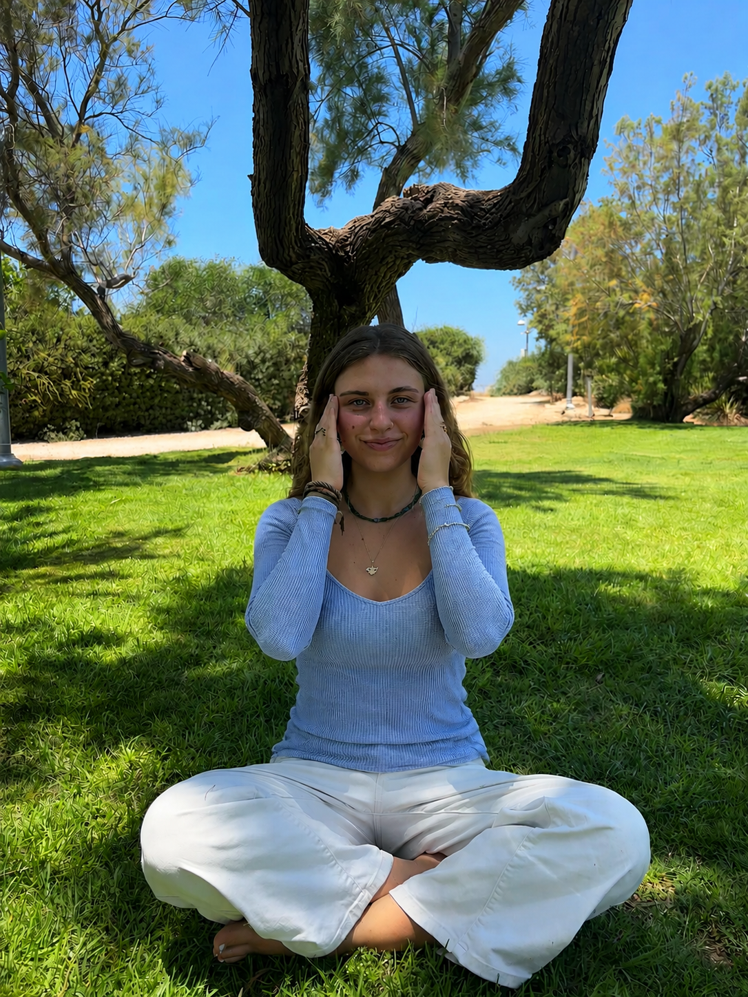 Aura sitting outdoors and demonstrating EFT tapping points.